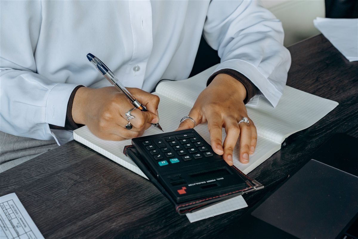 Chartered accountant at MASS Taxway Services preparing accounts with a calculator and ledger